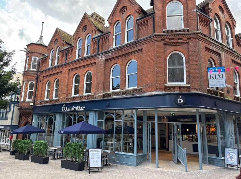 Modern café exterior at Suffolk New College with outdoor seating and large windows.