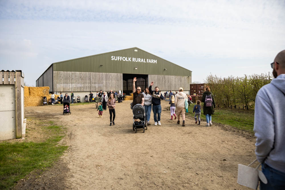 Families enjoy the 'lambtastic' spring fun day at Suffolk Rural Farm, with children and adults participating in farm activities and exploring the farm environment.
