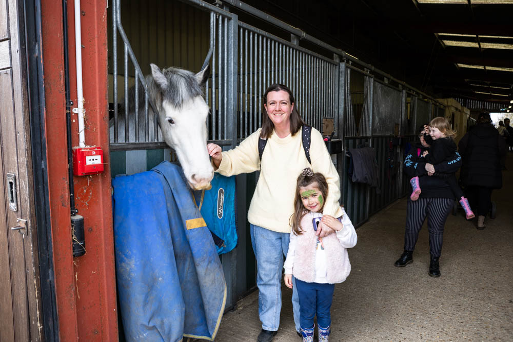 A woman and a young girl enjoy a visit to the stables at Suffolk New College during the spring family fun day, with children and families exploring farm animals and activities.