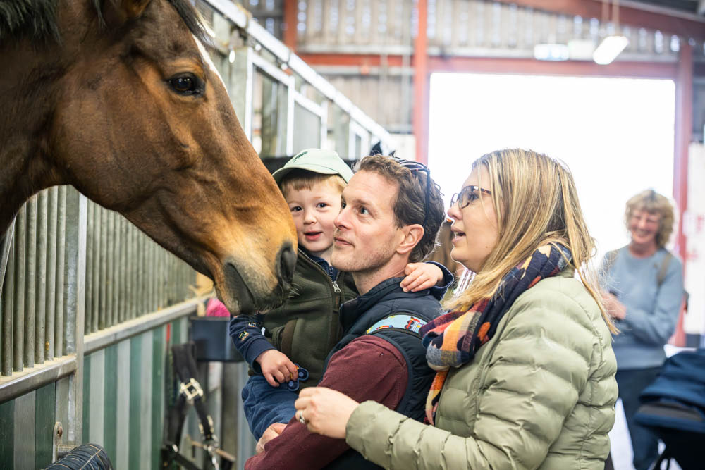 Family enjoying a spring day at Suffolk New College, interacting with a horse during the 'lambtastic' family fun event, attracting thousands of visitors.