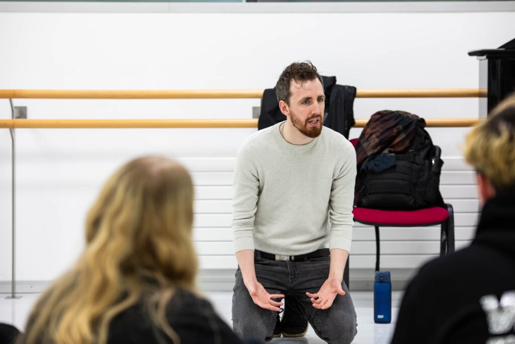 A dance instructor at Suffolk New College engaging students in a dance class, demonstrating skills in a studio with ballet barres and a focused learning environment.