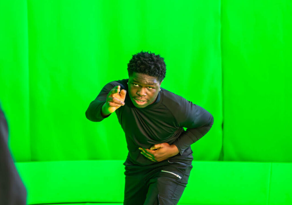 Two students practicing acting skills in front of a green screen at Suffolk New College, highlighting arts education and creative collaboration.