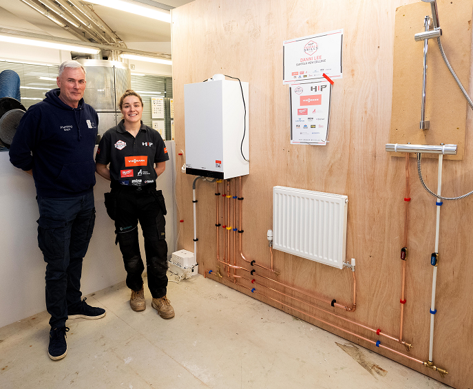 A young apprentice plumber with an instructor in a training workshop, demonstrating plumbing systems and equipment at Suffolk New College.
