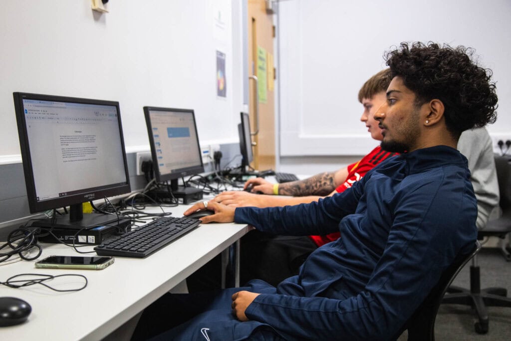 Two students in a classroom working on computers, focusing on digital industries and technology skills at Suffolk New College.