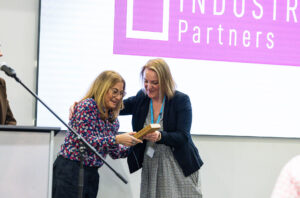 Two women exchanging a certificate at Suffolk New College during the annual dinner, celebrating reaching 200 industry partners and fostering strong industry collaborations.