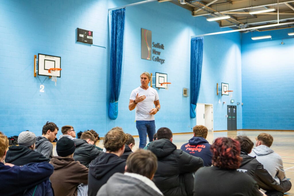 Suffolk New College instructor engaging students in a classroom with blue walls and basketball hoops, promoting STEM education and inspiring future space explorers.