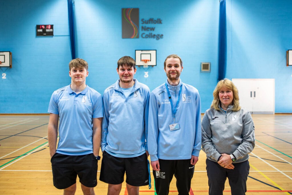 Group of four students and instructor standing in Suffolk New College sports hall, showcasing sports facilities and fitness activities.