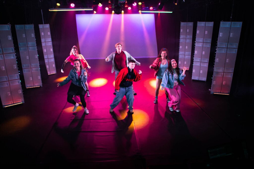 Students performing a dance routine inspired by Stranger Things on stage at Suffolk New College, showcasing their production skills and creativity in a vibrant theatre setting.