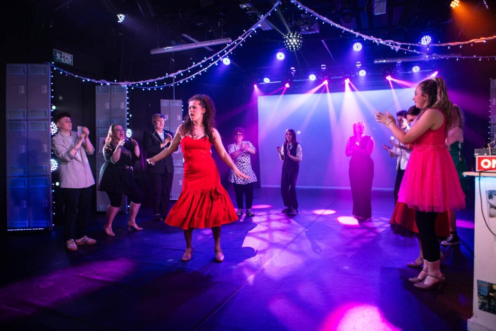 Students performing a dance on stage inspired by Stranger Things at Suffolk New College, showcasing creative production skills and college talent.