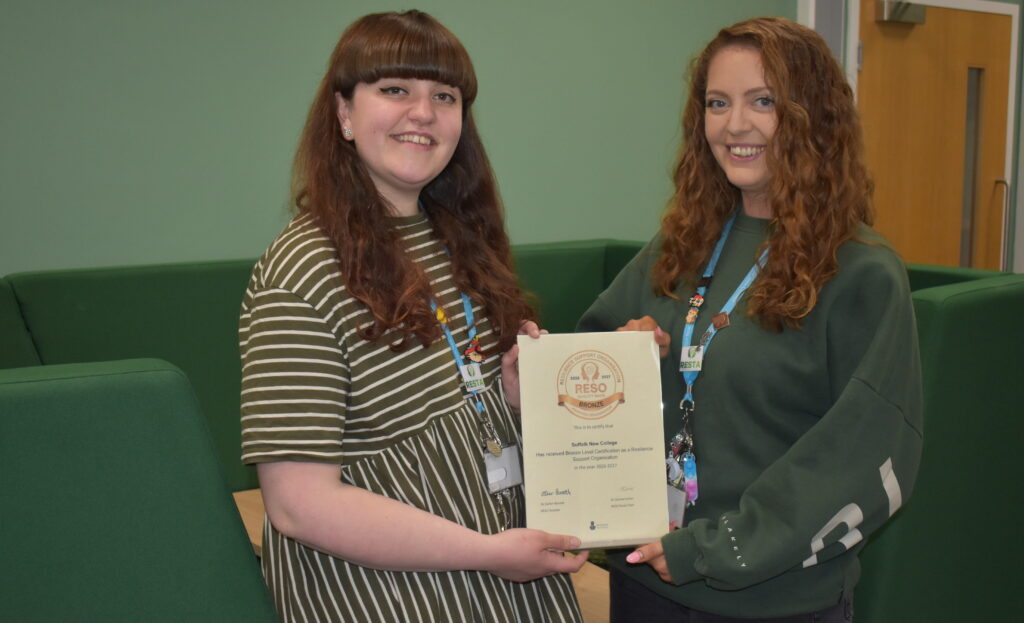 Two smiling female students at Suffolk New College holding a certificate during an award ceremony, showcasing student achievement and college success.