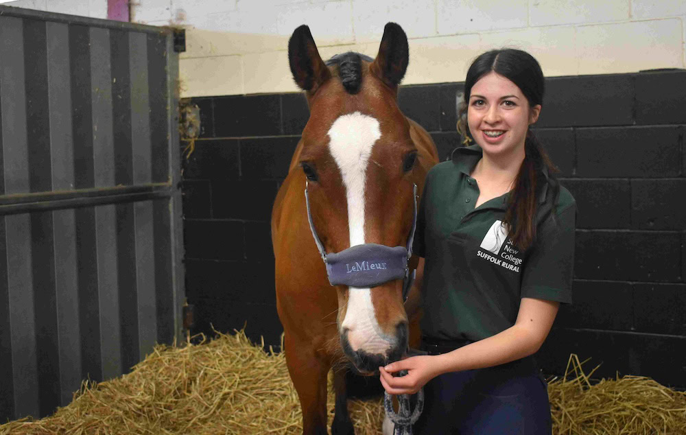 A young woman from Suffolk New College smiling and holding a horse's bridle during the annual family fun day, showcasing college activities and community engagement.