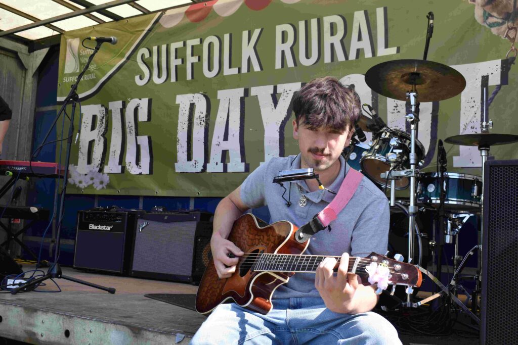 Young musician playing guitar on stage at Suffolk Rural Big Day Out during family fun day event.