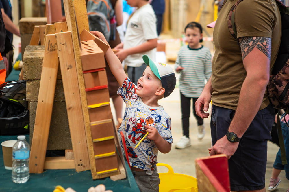 Young boy enjoying hands-on activities at Suffolk New College's family fun day, surrounded by children and adults in a lively outdoor event.