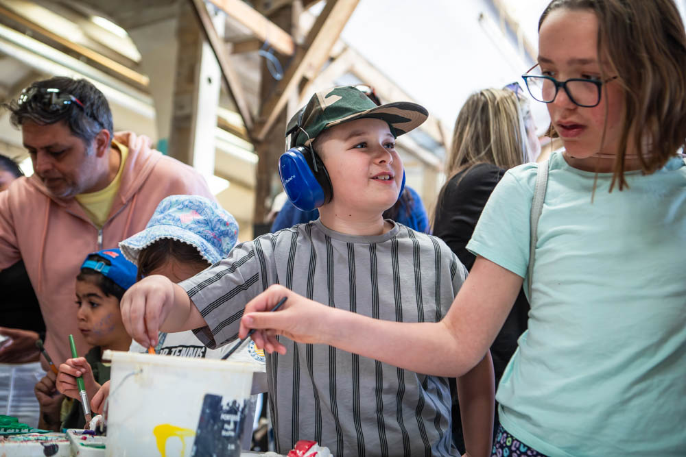 Children and families enjoying outdoor activities at Suffolk New College during the annual family fun day, with sunshine and engaging educational events.