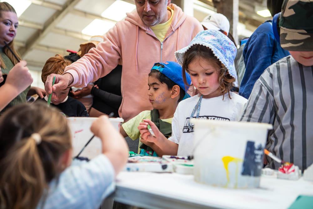 Children and families enjoying arts and crafts activities at Suffolk New College during the annual family fun day, with sunshine and community engagement.