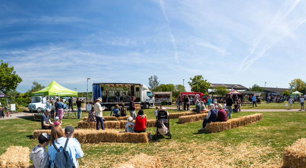 Families and children participating in outdoor activities and entertainment during Suffolk New College's annual family fun day on a sunny day.