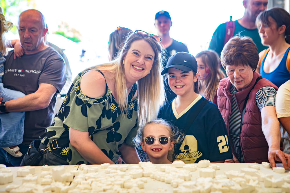 Families enjoying the annual Suffolk New College family fun day in the sunshine, with children and adults engaging in outdoor activities and community events.