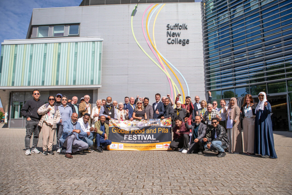 Group of diverse students and staff at Suffolk New College celebrating the Global Food and Pita Festival outside the college building.