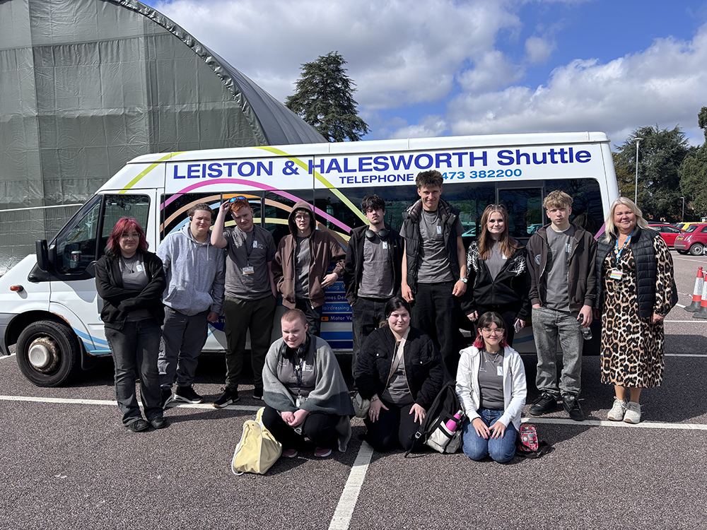 Group of students and staff from Suffolk New College posing in front of a shuttle bus after achieving third place in a national maths competition, celebrating academic success.