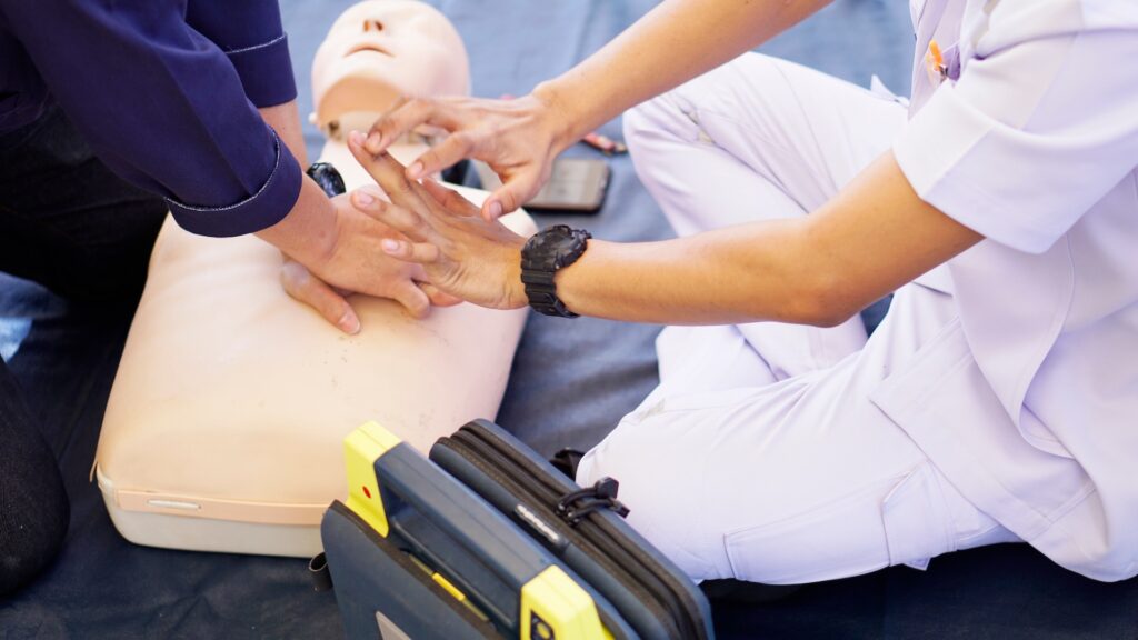 Students practicing CPR techniques on a mannequin during a healthcare training session at Suffolk New College, focusing on first aid skills and emergency response education.