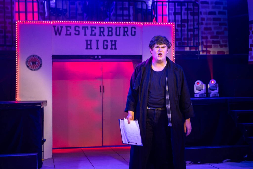 Student performing on stage at Suffolk New College during a drama production, with a backdrop reading Westerburg High, showcasing college arts and theatre courses.
