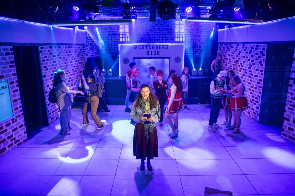 Students performing on stage at Suffolk New College theatre, showcasing drama and performing arts facilities with vibrant lighting and a lively atmosphere.