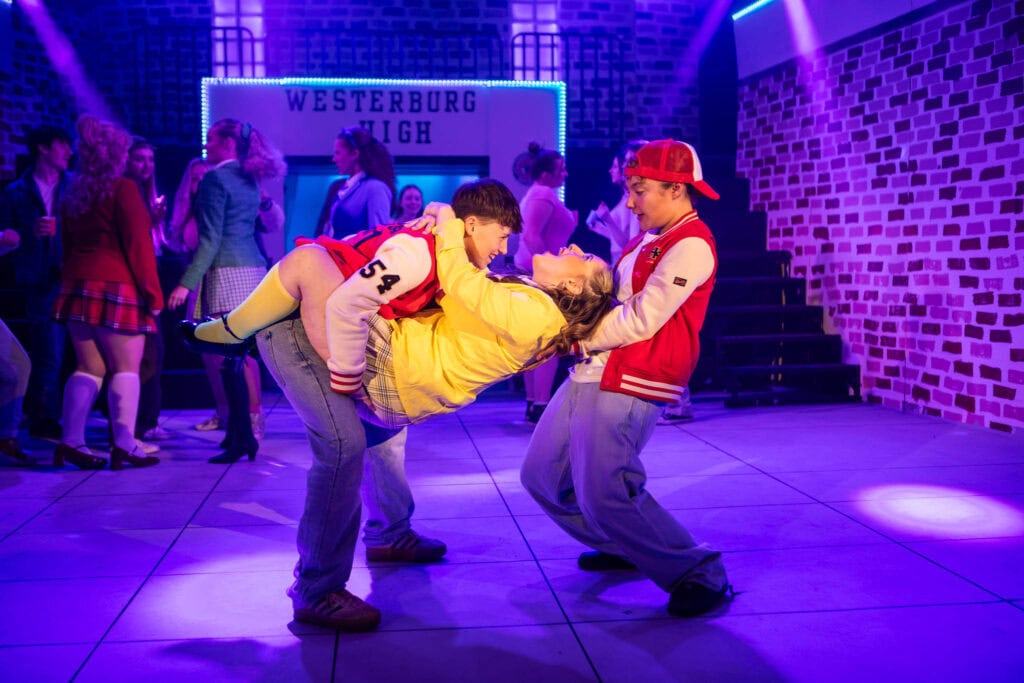 Students performing a dramatic scene on stage at Suffolk New College, showcasing drama and performing arts education in a vibrant college environment.