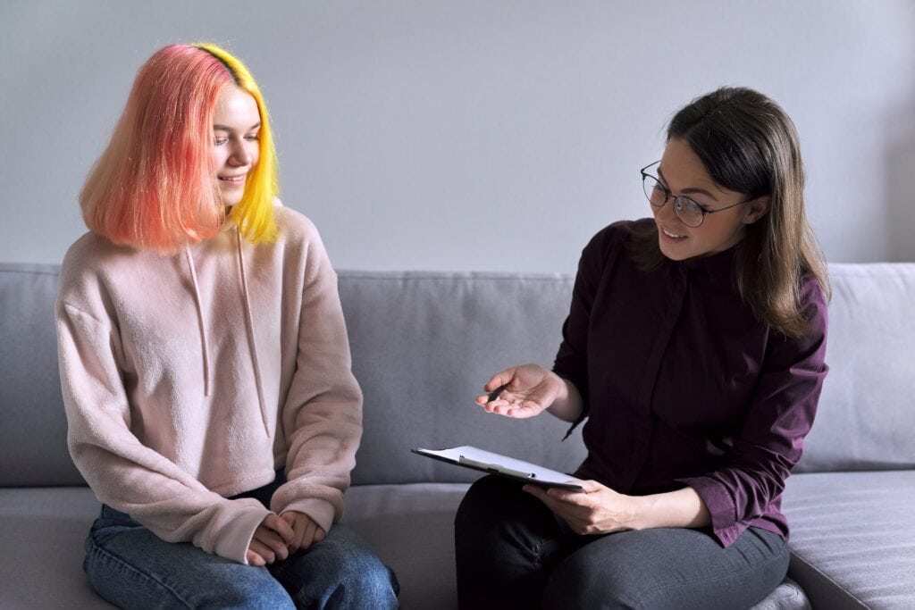 Two students at Suffolk New College engaging in a discussion, one holding a notebook, highlighting college support and student engagement in a modern learning environment.