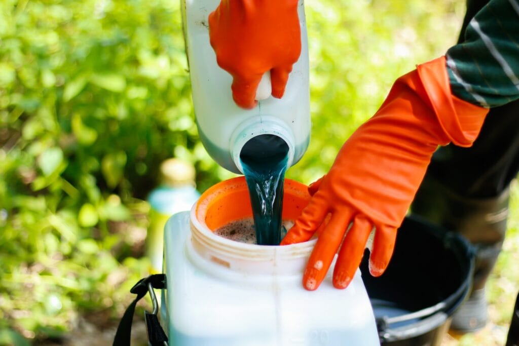 Student wearing orange gloves pouring dark soil or compost into a white container outdoors, demonstrating practical horticulture skills at Suffolk New College.