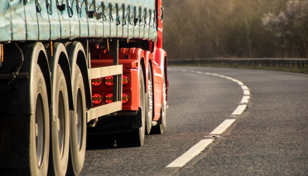 A large red truck driving along a curved road, showcasing transportation and logistics training facilities at Suffolk New College in Suffolk, UK.