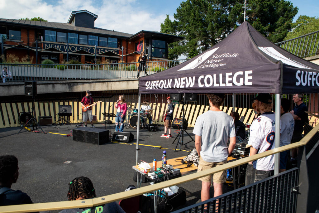 Students showcase creative careers on stage at Suffolk New College theatre during a college event, with a live band and audience in attendance.