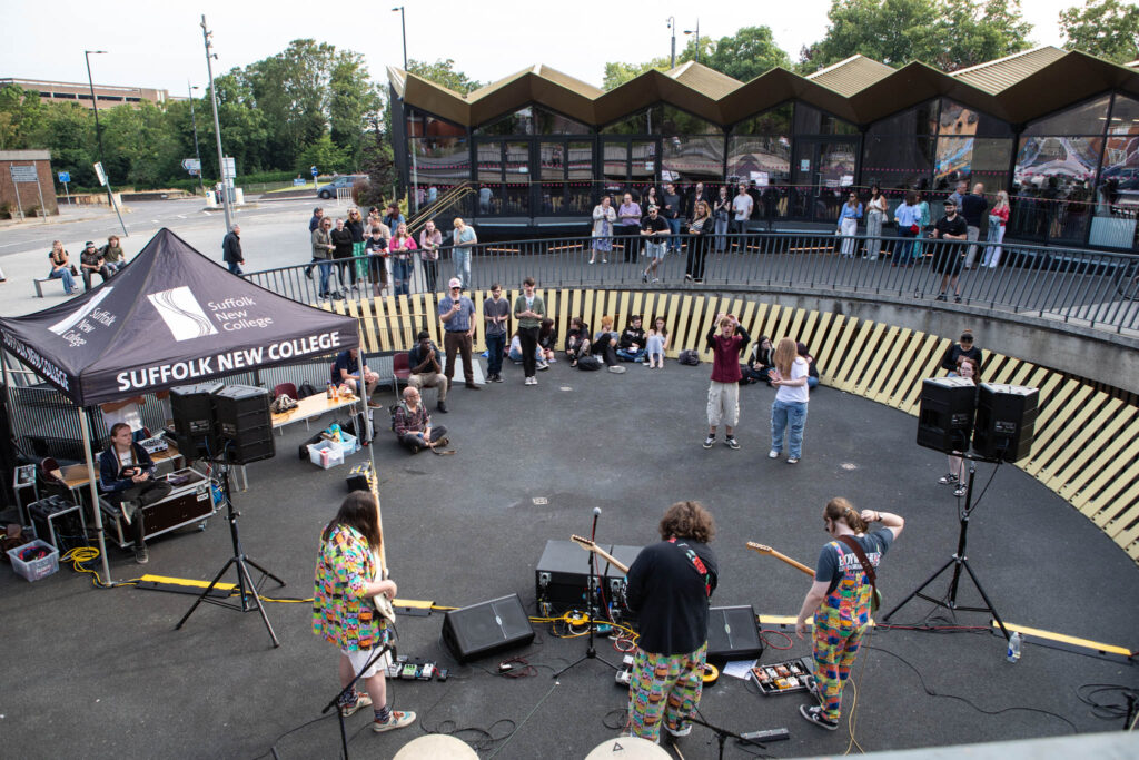 Students showcase creative careers with a live performance in an outdoor theatre at Suffolk New College, engaging the community and highlighting creative arts programs.
