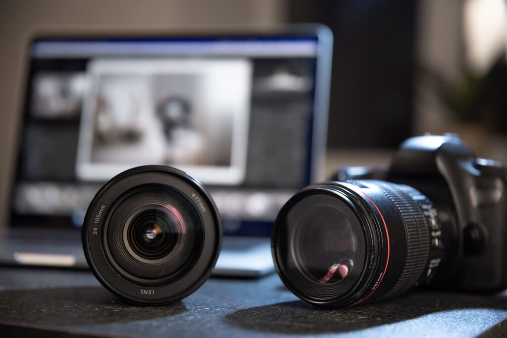 Close-up of professional camera lenses and a laptop on a desk, representing digital media and creative design at Suffolk New College.