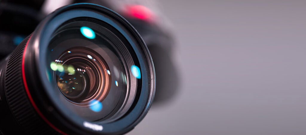 Close-up of a professional digital camera lens with reflections and bokeh effects, highlighting photography equipment at Suffolk New College.